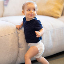 Kudos diaper worn by a baby standing beside a sofa