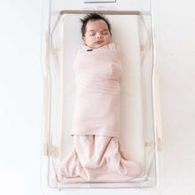 Pink baby sleep bag swaddler on sleeping infant in open bassinet
