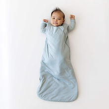 Light blue baby sleep sack worn by an infant with arms raised