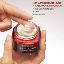 Face moisturizer jar with white cream swirl on open lid, held in hands