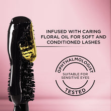 Mascara wand coated in glossy black gel beside a rose-gold mascara tube
