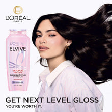Pink L'Oreal Elvive glycolic + gloss shine boosting shampoo bottle beside dark hair