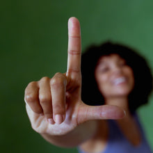 Hand showing a peace sign in front of a softly blurred background