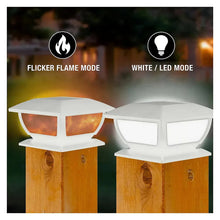 Two white solar post cap lights on wooden posts, one amber-lit and one white-lit