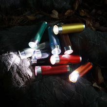 Multicolor LED flashlights with lit beams and silver front caps on rock