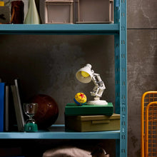Tabletop robotic spotlight model with yellow bulb on a shelf