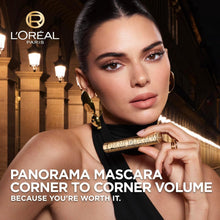 Black mascara wand held near eye; volumized lashes and defined eye makeup look