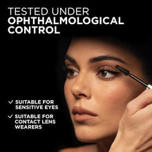 Black mascara applicator brush near eye on face; defined lashes makeup