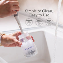 Lansinoh anti-colic baby bottle being washed, clear bottle with purple rim