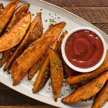 Roasted potato wedges with herb garnish and red dipping sauce