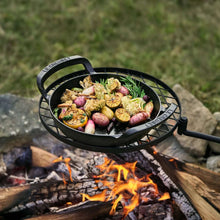 Le Creuset Alpine skillet with grilled vegetables inside on a wire grate over flames