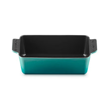 Cast iron loaf pan in teal with black interior and side handles, front angle view.