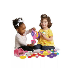 Children playing with pink musical teapot, cups, plates, and cupcake carry case