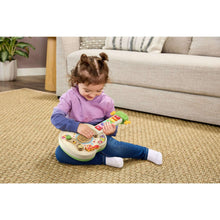 Child sitting and playing with a wooden strum-and-count guitar toy with color buttons