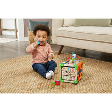 Wooden activity cube toy with colorful handle bars and number panels, next to toddler