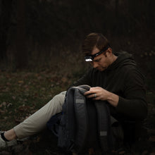 LED headlamp worn on forehead with black strap and orange trim on a hoodie