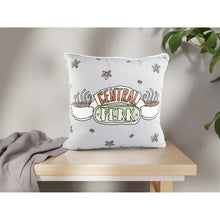 White Central Perk logo decorative pillow on a shelf with flower accents.