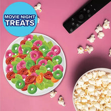 Dish of assorted fruit gummy rings with popcorn pieces nearby