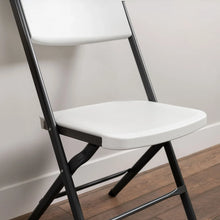 Close-up of white folding chair seat and contoured back with black steel frame