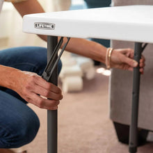 Fold-in-half adjustable table with white tabletop and dark metal folding legs