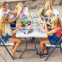 White folding table with black legs in outdoor family setting