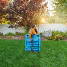 Blue children’s picnic table being held and carried outdoors on grass.
