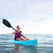 Blue youth sit-on-top kayak on water with paddling child and paddle visible.