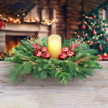 Lighted evergreen centerpiece with red ornaments and a lit candle