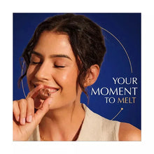 Person tasting a chocolate truffle, smiling with hands holding a bite-sized piece