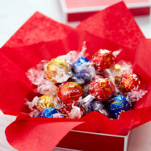 Assorted chocolate truffles in red box with wrapped Lindor candies