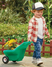 Green ride-on tractor with attached cart and yellow seat; child in plaid shirt