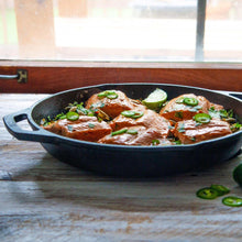 Black cast iron skillet with two handles, filled with sliced meat