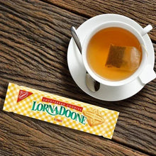 Shortbread cookie pack beside a cup of tea on a wooden table