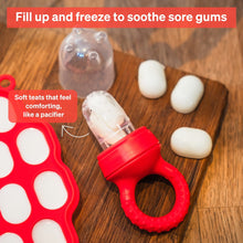 Red and clear baby fruit feeder with soft teat and teether ring on wooden surface