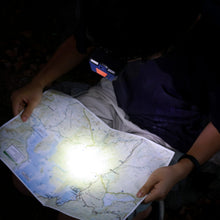 Blue LED headlamp worn on a person, shining light on a map