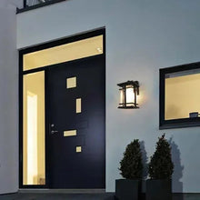 Black outdoor LED wall lantern beside a front door with clear glass side panels