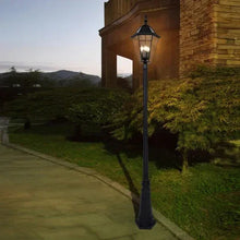 Black outdoor solar post light with lantern-style glass shade on a tall post