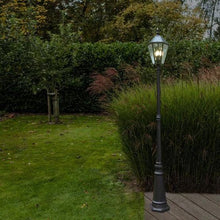 Two black solar post lights lit along a garden path and grass edge
