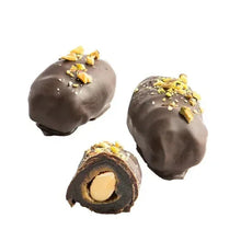 Chocolate-covered dates with pistachio crumbs, two whole and one sliced pieces