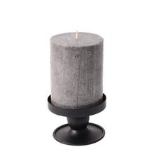 Black flippable candle holder holding a tall pillar candle