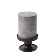 Black flippable candle holder with pedestal stand holding a gray pillar candle
