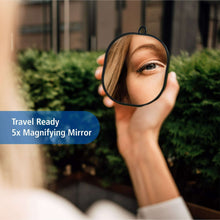 5x magnifying travel vanity mirror with black frame held near the face