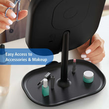Black makeup mirror with storage tray base holding small bottles and tools