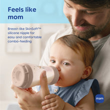 Baby drinking from a 9 oz anti-colic bottle with clear nipple and beige base, MAM