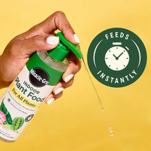 Hand holding Miracle-Gro indoor plant food bottle with green pump and drips
