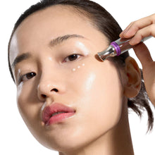 Retinol eye cream applicator held near the eye with a purple tip