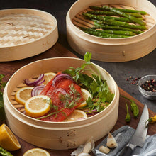 Two bamboo steamer baskets with lid open, fish and lemon inside, beige