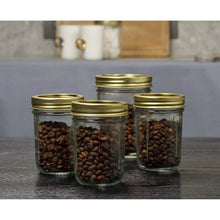 Small glass canning jars with gold lids and rings, filled with coffee beans