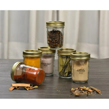 Small glass canning jars with gold lids and rings, filled with spices and powders