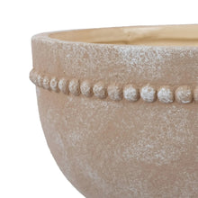 Close-up of cream textured ceramic plant pot rim with bead-like dot pattern